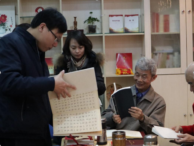 老同志们兴致勃勃地观看天津师大学古籍保护志愿服务团队的文创作品